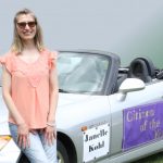 Janelle seated on bonet of a sports car that was used in a parade